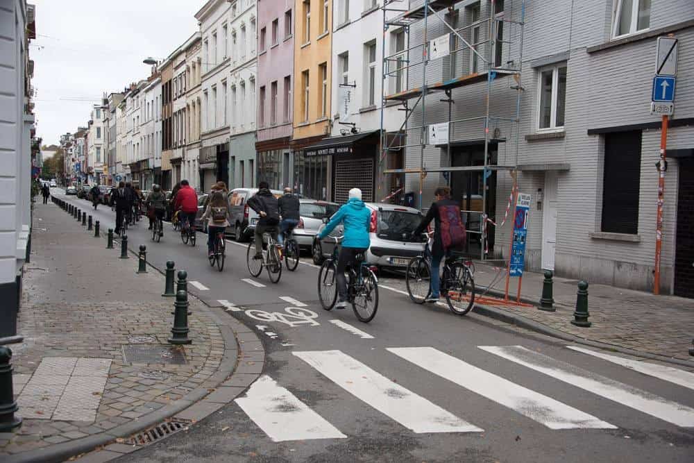 Cyclistes participant au festival ANTE à Bruxelles dans une rue urbaine animée.