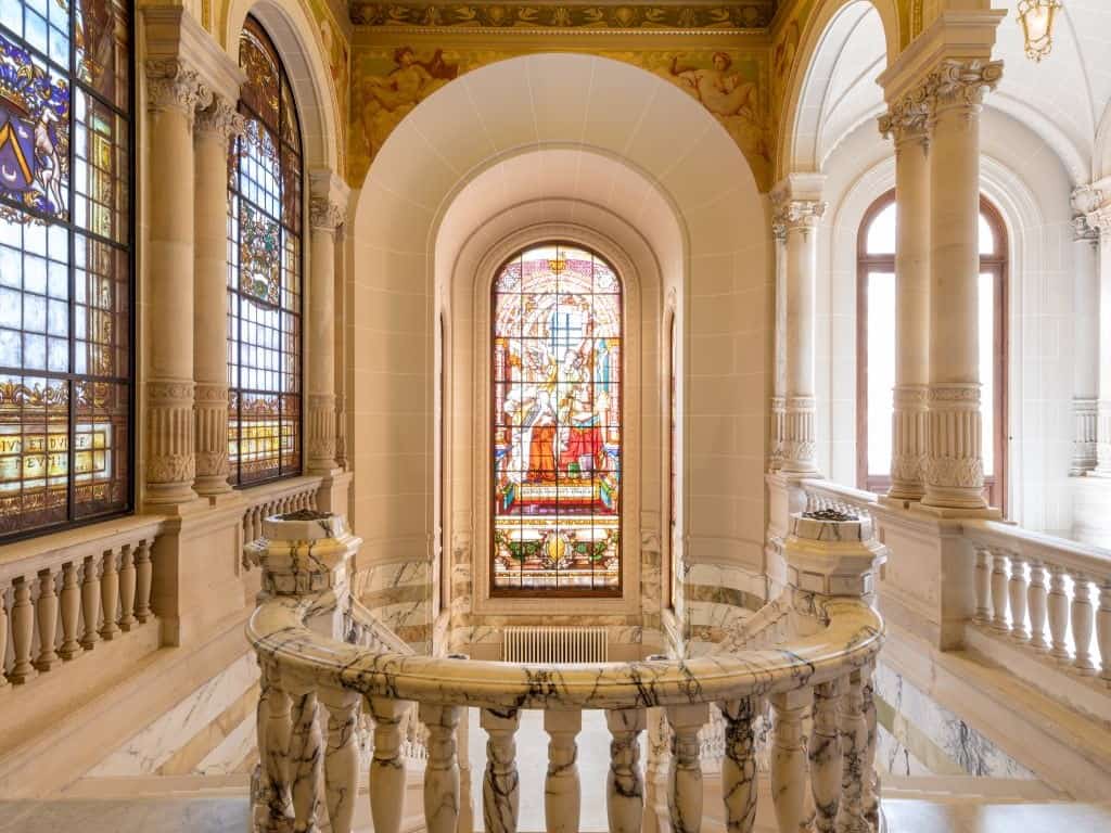 Vitrail coloré dans un bâtiment historique, avec architecture élégante et détails en marbre.