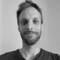 Photographe homme portrait en noir et blanc, visage souriant, style artistique.